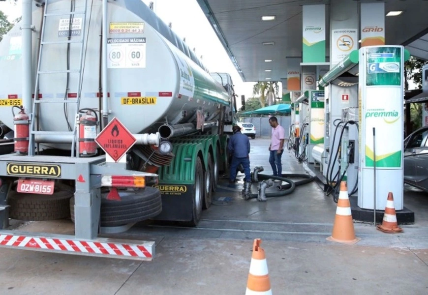 Caminhão tanque reabastecendo posto de combustível.