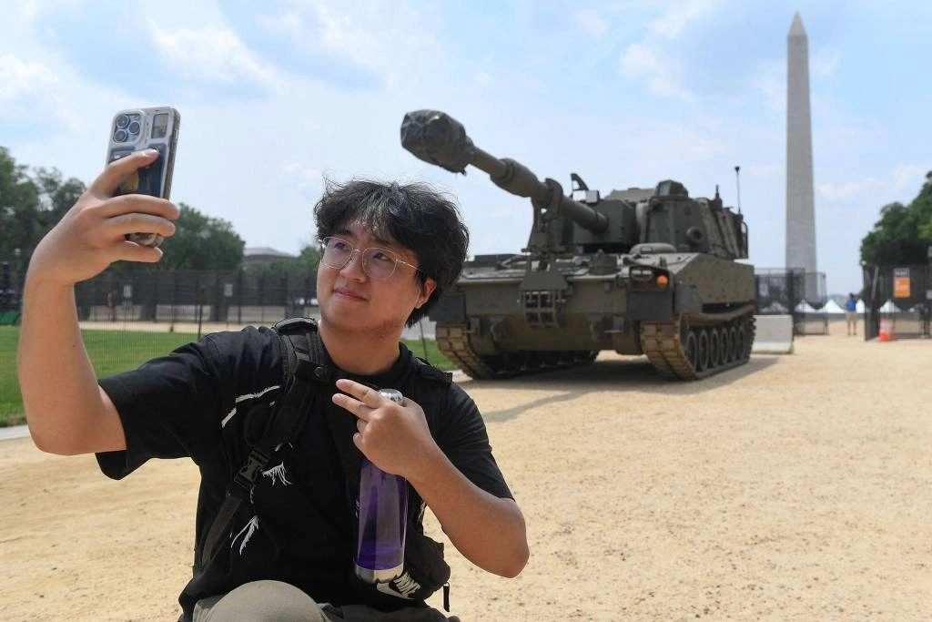 Jovem tira selfie em frente a um obuseiro autopropulsado M109 Paladin no National Mall, em Washington