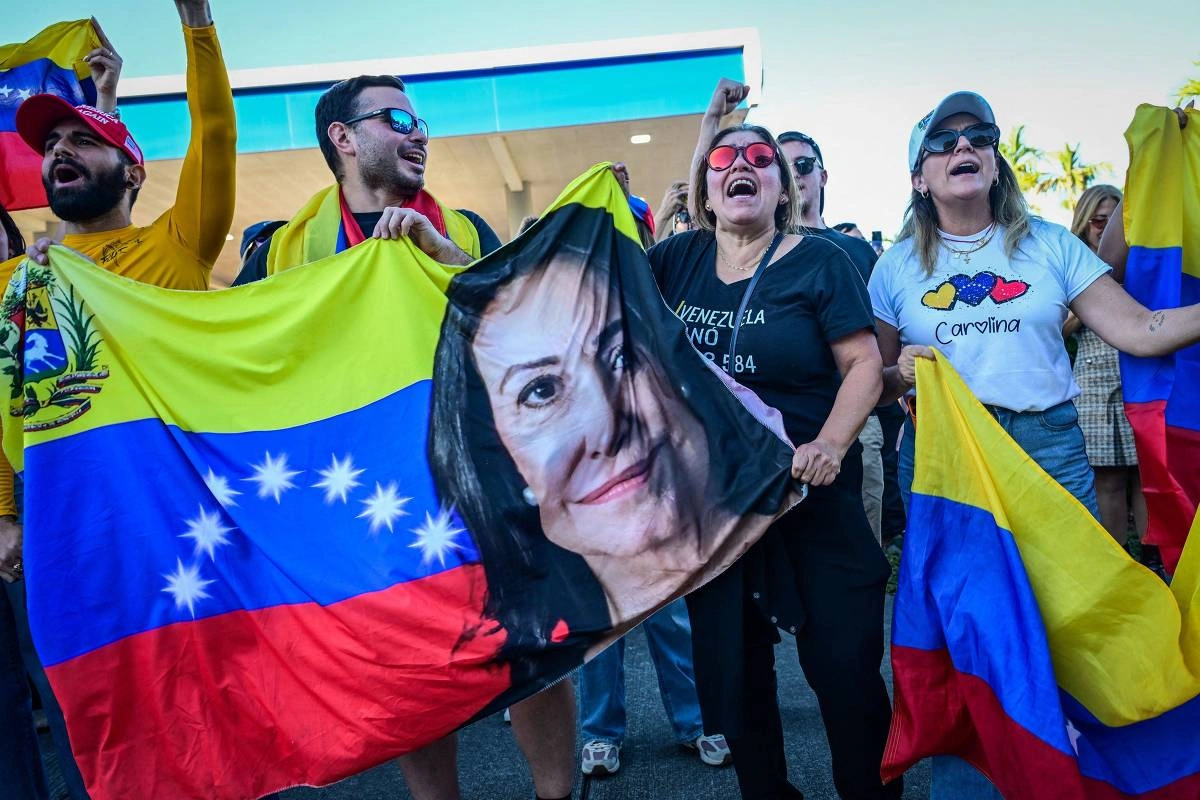 Manifestantes seguram bandeira da Venezuela com o rosto de María Corina Machado, líder opositora, durante ato anti-Maduro em Miami, nos EUA