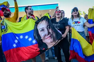 Manifestantes seguram bandeira da Venezuela com o rosto de María Corina Machado, líder opositora, durante ato anti-Maduro em Miami, nos EUA (Foto: Giorgio Vieira/AFP)