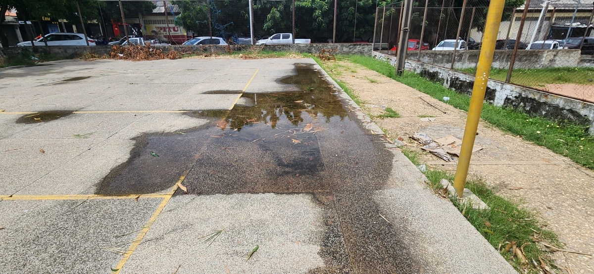 Água parada na quadra de esporte por falta de regularidade da superfície e da falta de drenagem