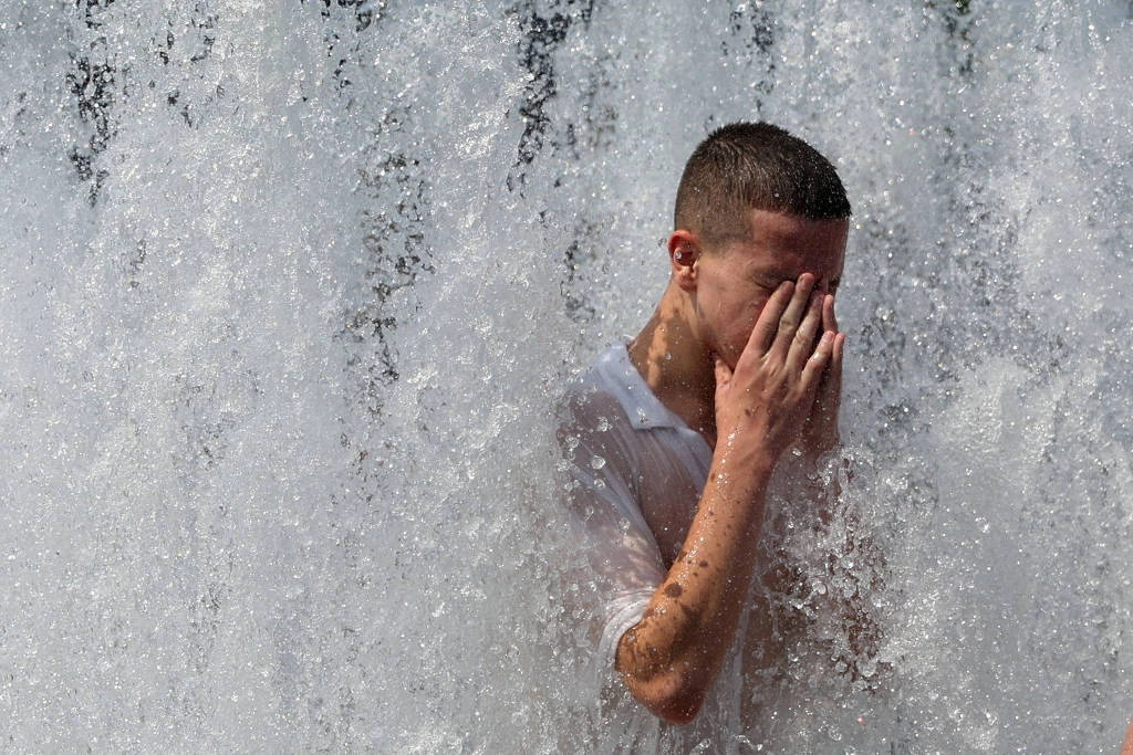 Pedestre se refresca na fonte em frente à Catedral de Berlim, Alemanha, durante a onda de calor