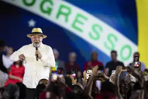 Homem de camisa branca e chapéu bege segura microfone e fala para público que registra com celulares. Ao fundo, parte da bandeira do Brasil com a palavra 'PROGRESSO'. Convenção nacional do Partido dos Trabalhadores (PT) que oficializa a candidatura do presidente Luiz Inácio Lula da Silva à reeleição para a Presidência da República (Foto: Reprodução)